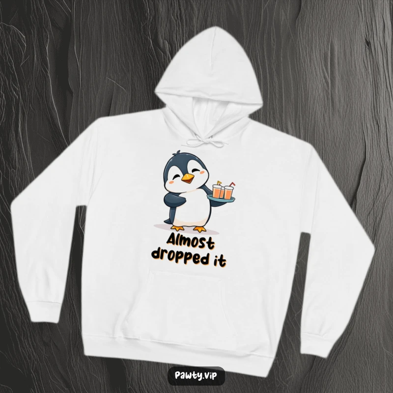 Funny hoodie with a flustered penguin tripping slightly while holding a tray of drinks, offering warmth and a touch of relatable humor.
